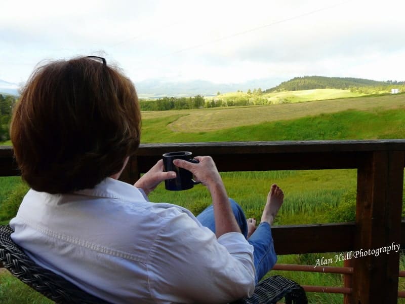 woman on a deck drinking coffee looking at the mountains