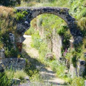 stone arch surrounded by grass and trees in Syracuse, Sicily