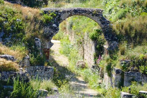 stone arch surrounded by grass and trees in Syracuse, Sicily