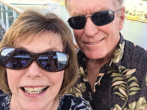 Boomer woman and man smile as their luxury cruise ship leaves port