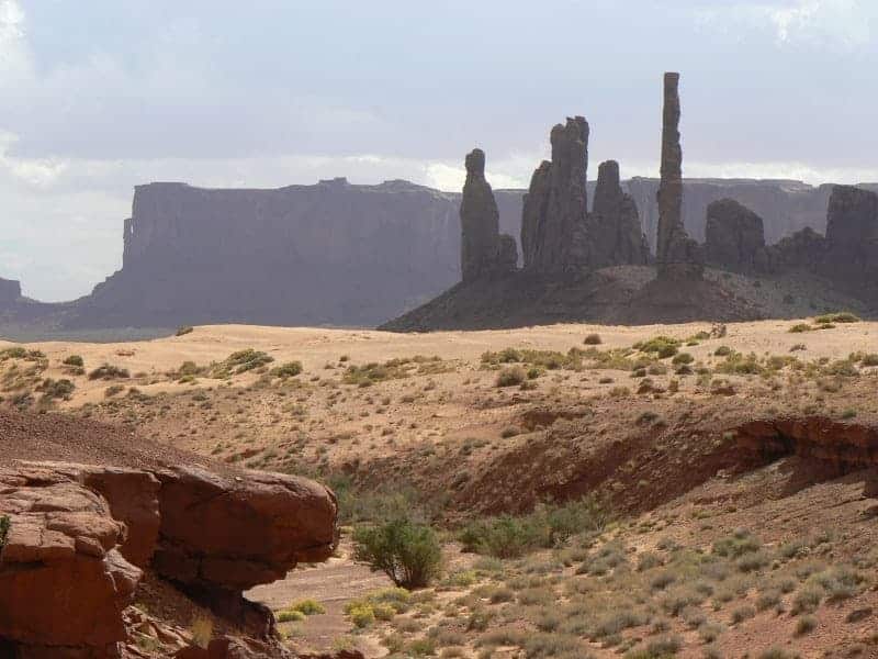 Totem pole formations with Hunt Mesa rising behind in Monument Valley.