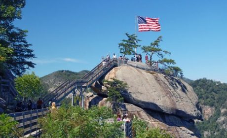 stairs leading up to large rock with american flag