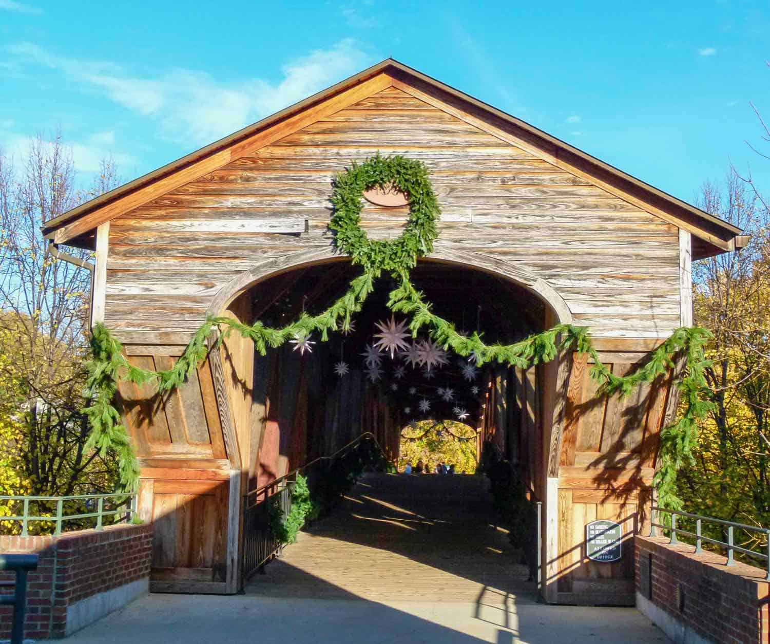 A brown covered bridge decorated with Christmas greenery at the entry to Old Salem near Winston-Salem.