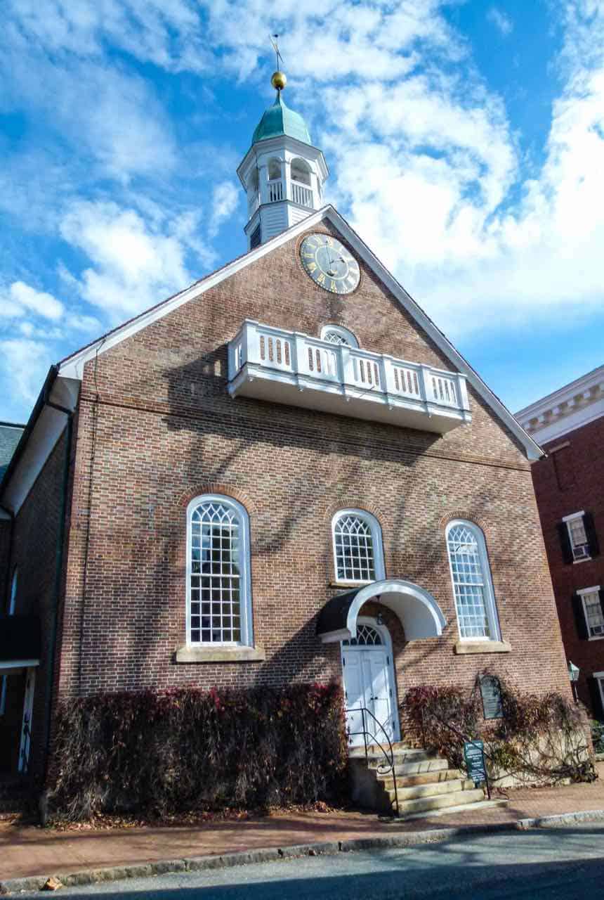 Historic Moravian brick church with a clock and balcony on the front in Old Salem, North Carolina.
