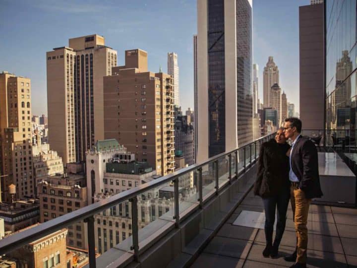 A couple standing on a balcony overlooking a city