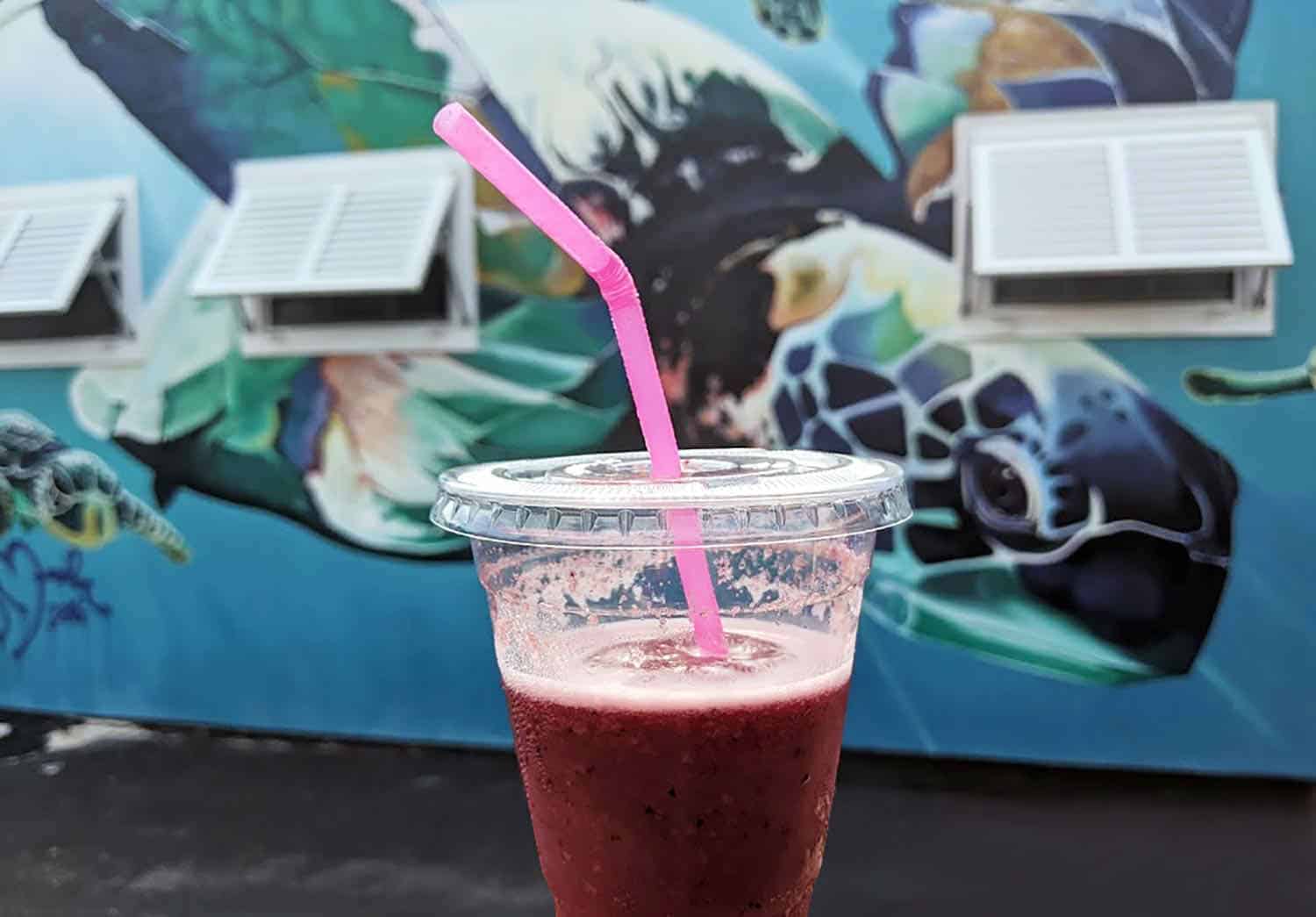 red-colored smoothie in front of a Melbourne, FLA mural