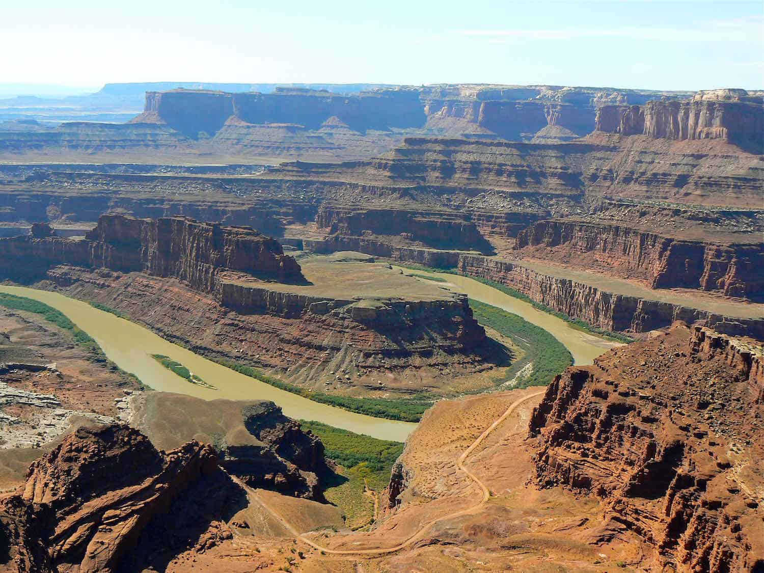 Muddy river winding through a canyon surrounded by cliffs at Dead Horse Point Overlook