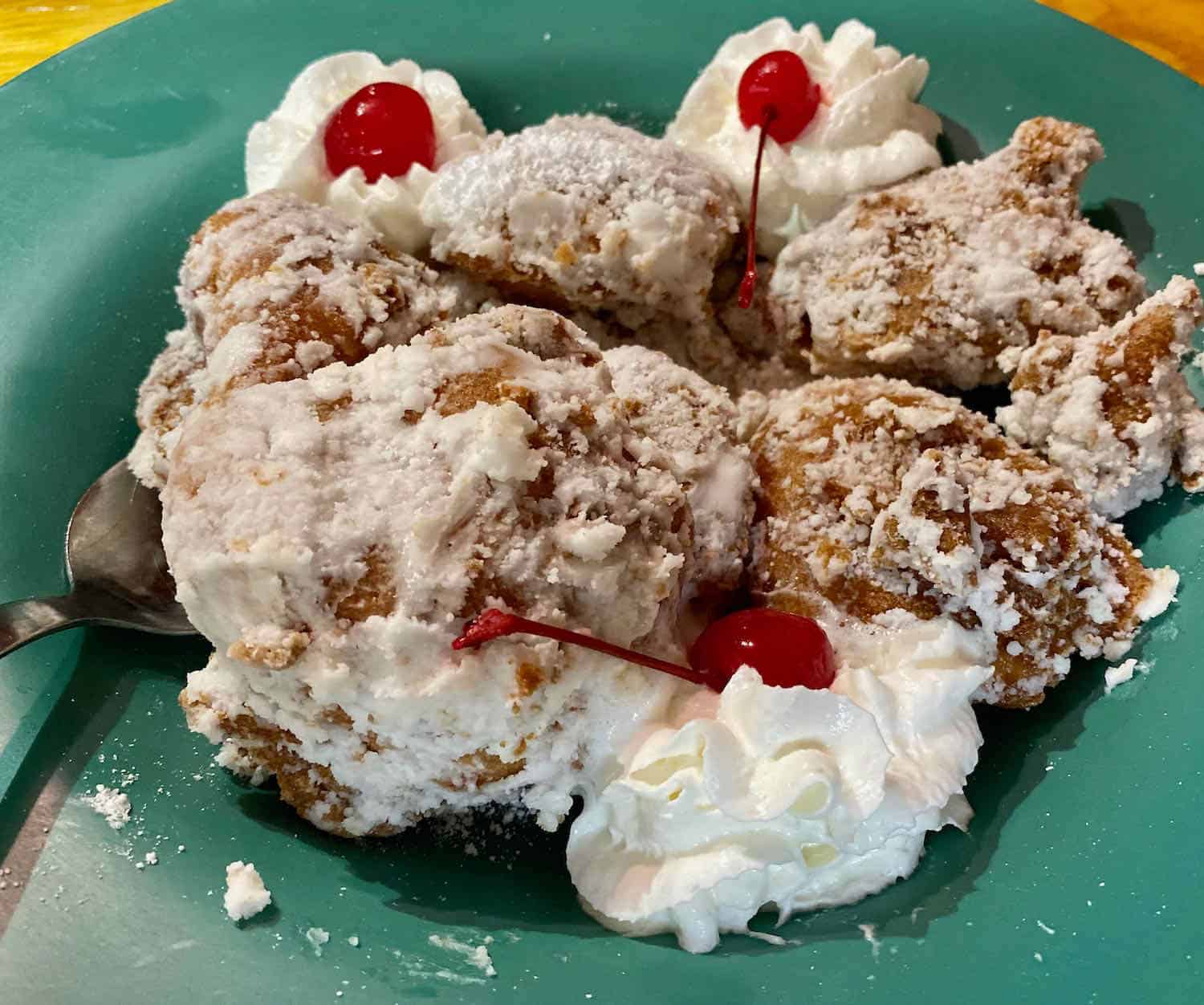 fruit fritters covered with whipped cream and topped by cherries