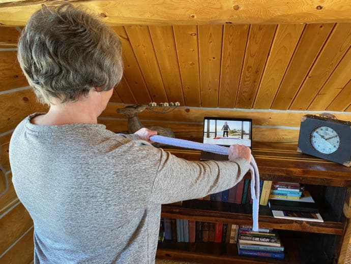 woman stretching by watching an online exercise class