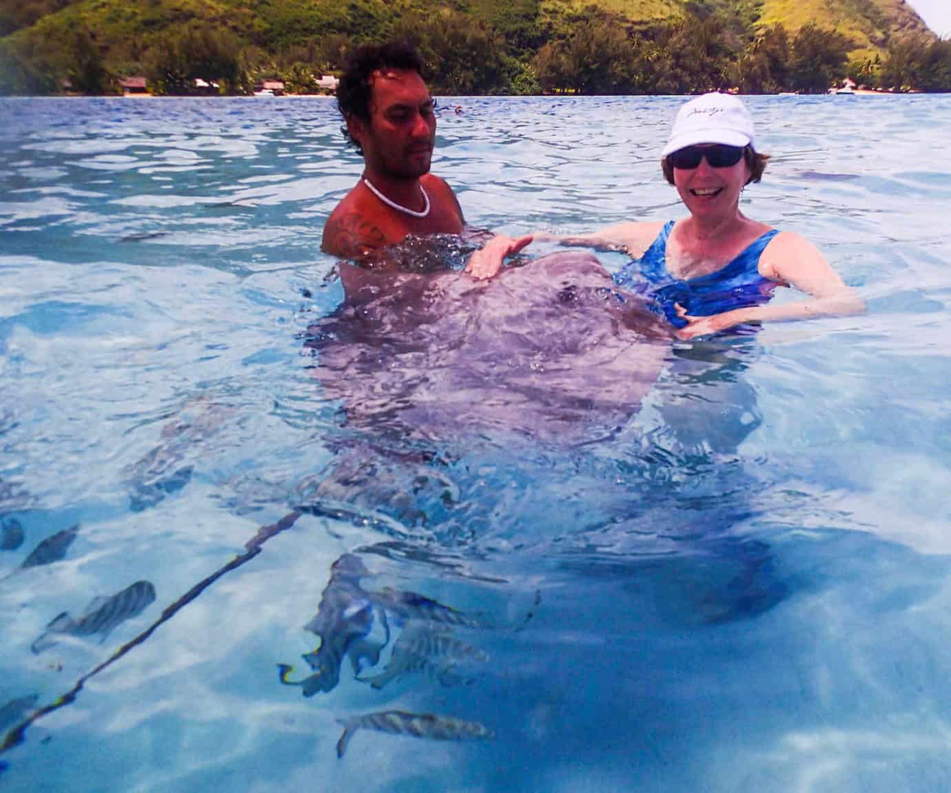woman and man in water touching a stingray