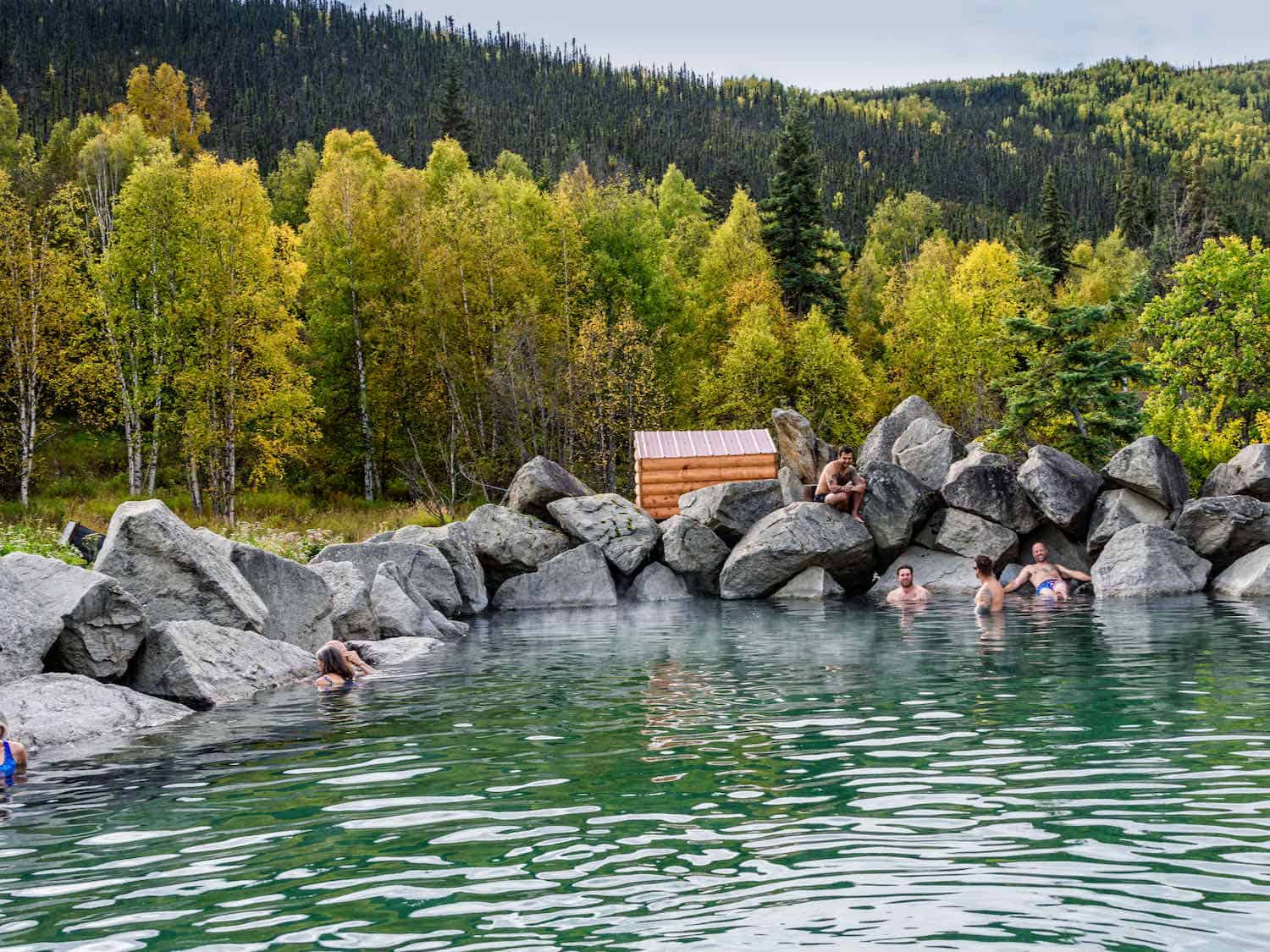 people soaking in a hot springs surrounded by the forest