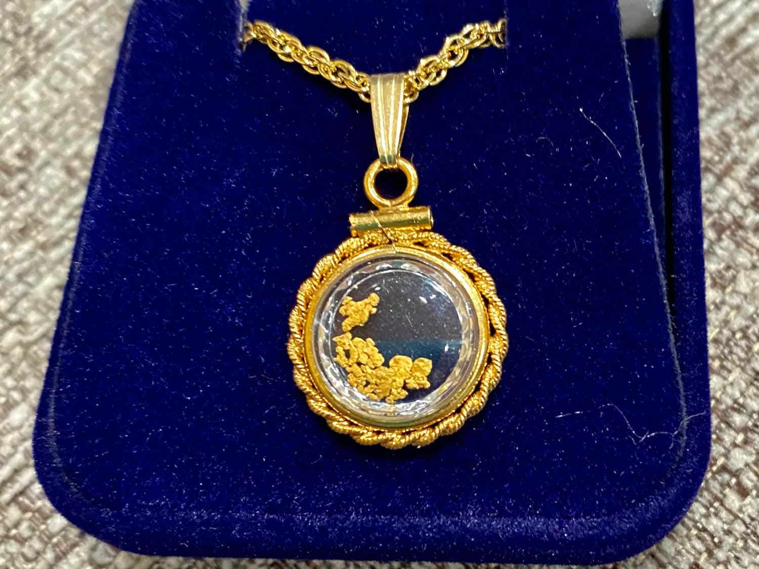 necklace holding flecks of gold in a dark blue case