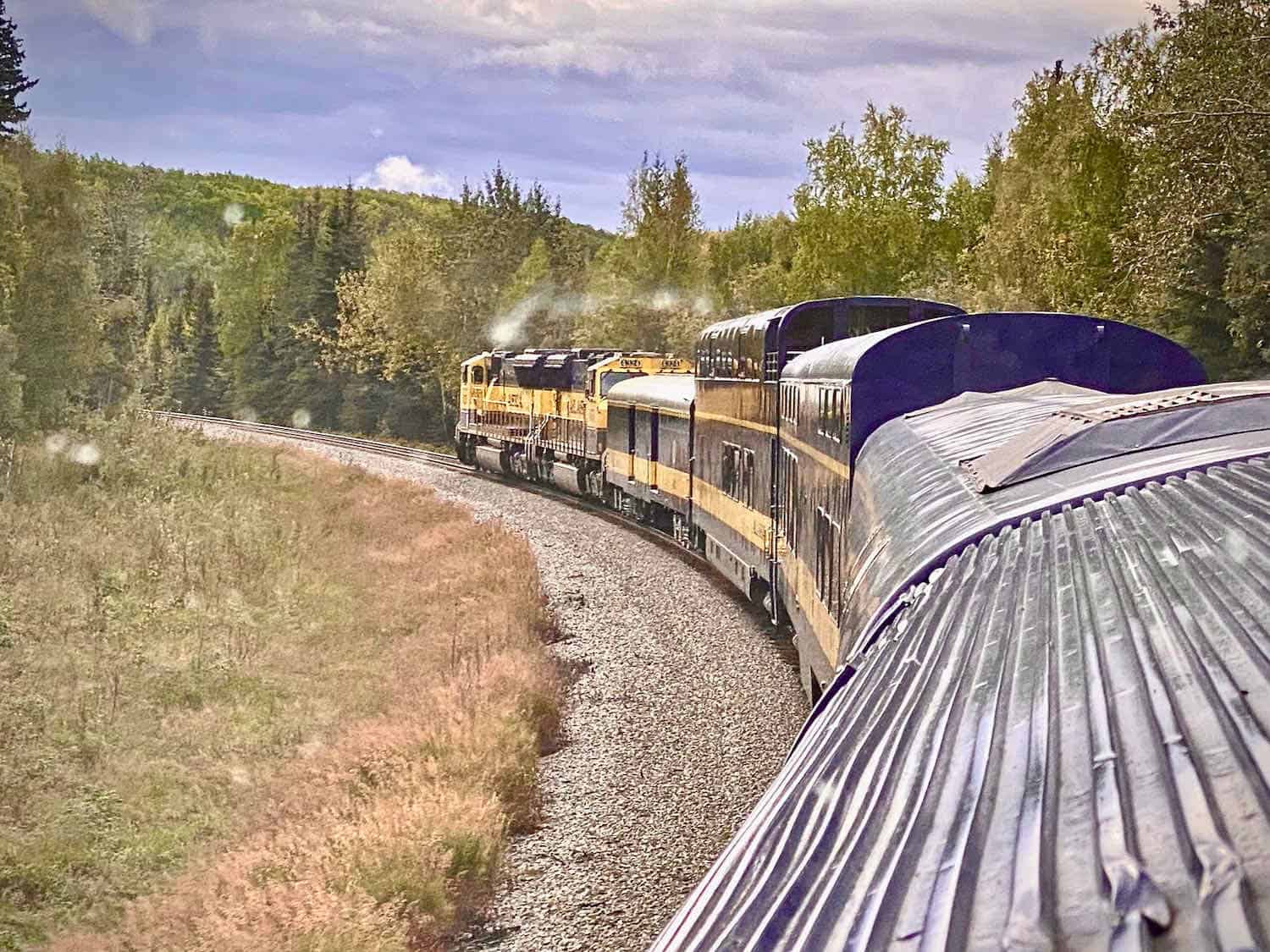 train from Fairbanks to Denali on the tracks with steam coming from engine.