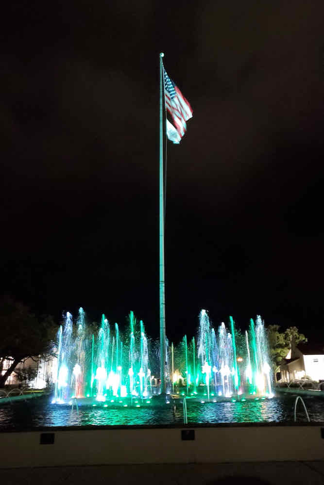 American flag at night surrounded by illuminated fountains