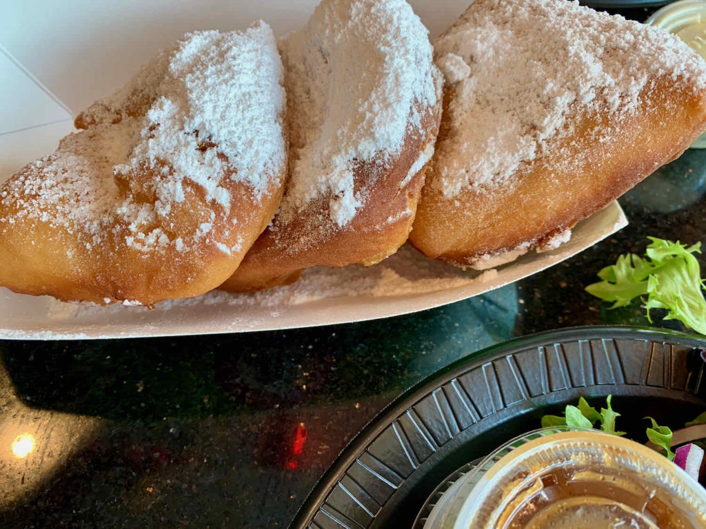 Powdered sugar covers a plate of beignets