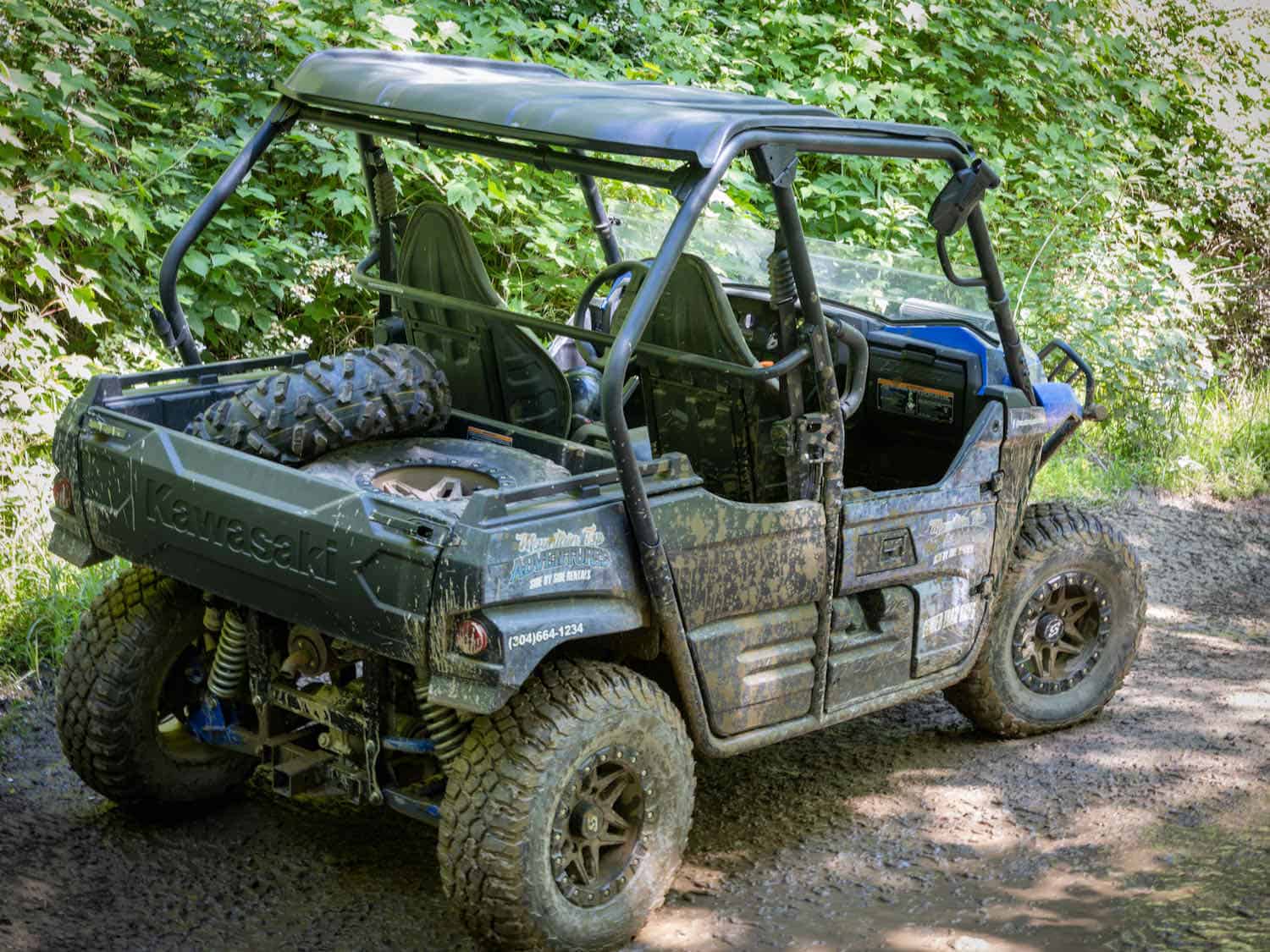 Muddy ATV parked on a trail.
