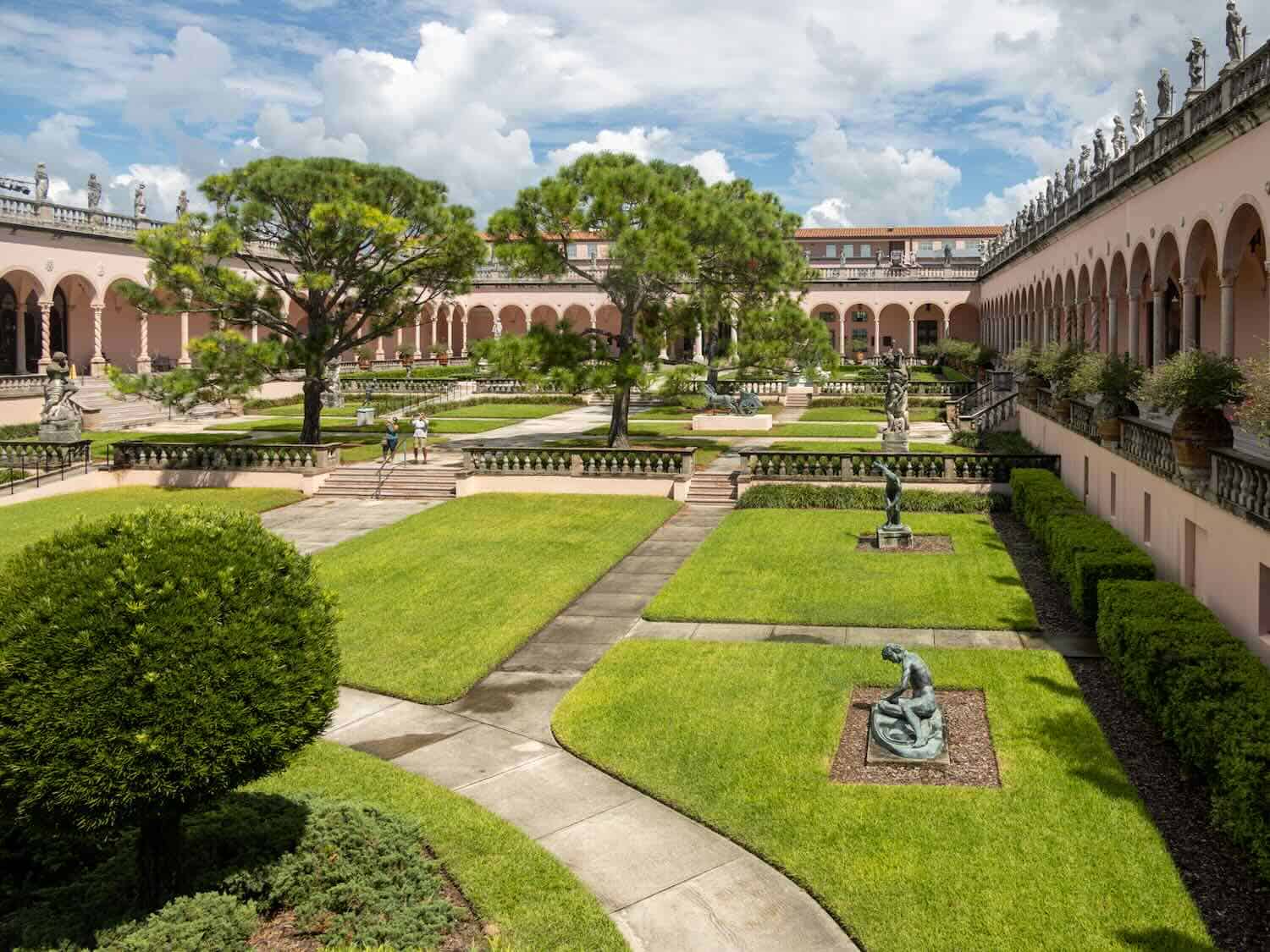 A formal garden at Ringling Museum of Art where patches of grass with sculpture in the center are separated by concrete walkways is one of the many cultural things to do in Sarasota, Florida.