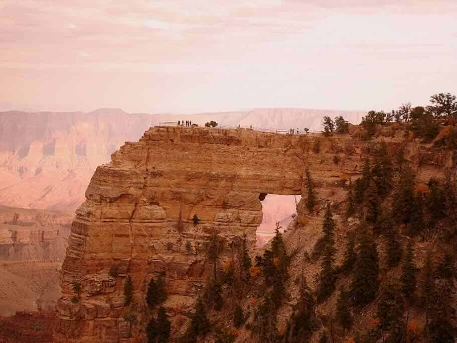 a natural sandstone bridge, known as Angel's Window, stretches out into the Grand Canyon from the North Rim.
