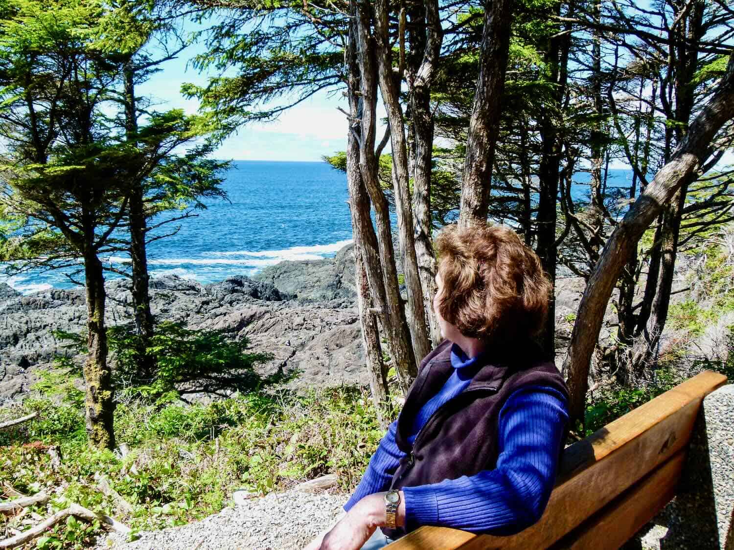 woman sitting on a bench looking at ocean from Wild Pacific Trail on Vancouver Island, B.C.
